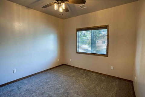 an empty living room with a window and a ceiling fan