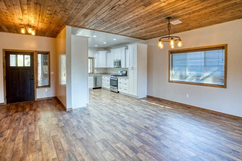 an empty living room with a kitchen in the background