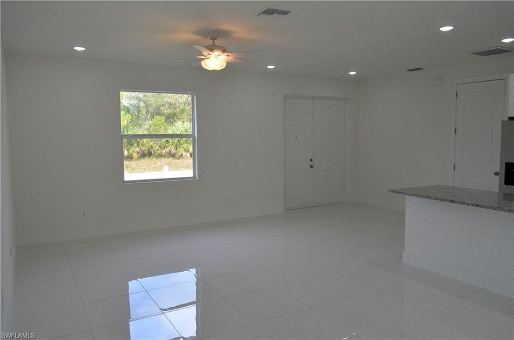 an empty living room with a ceiling fan and a window