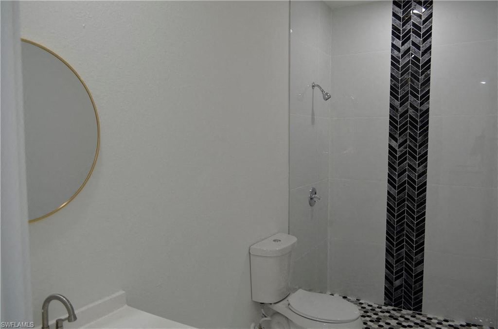 a white bathroom with a toilet and a shower