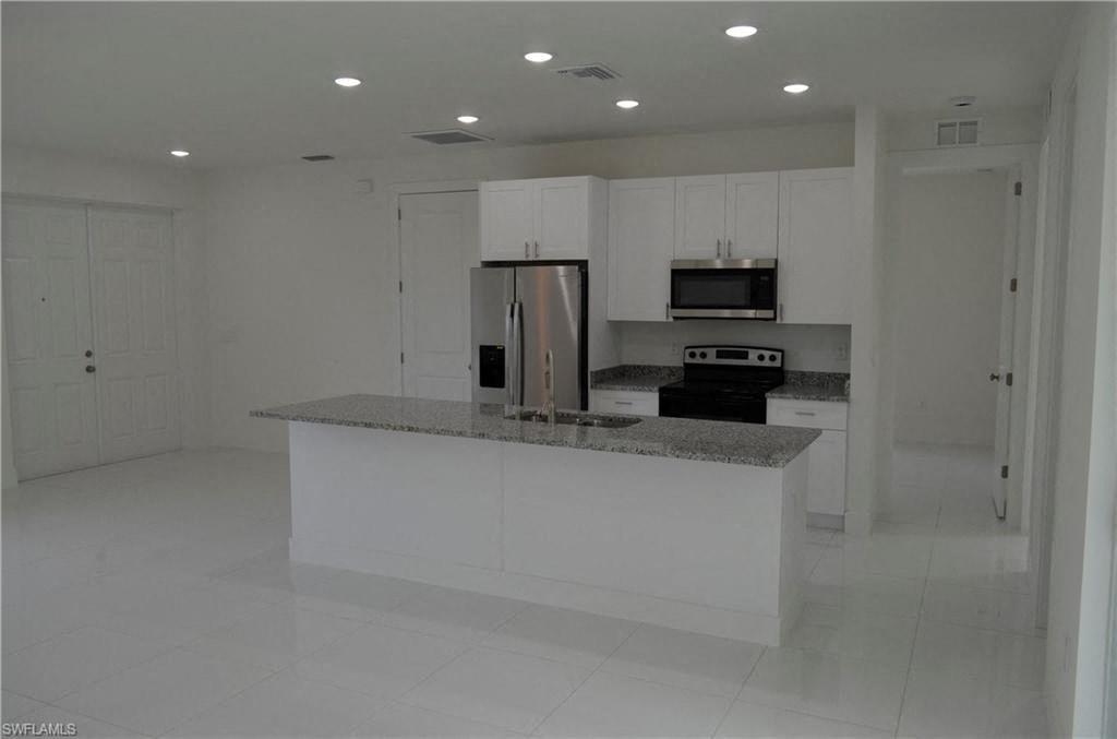 an empty kitchen with white cabinets and a counter top