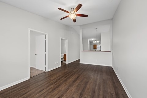 A room with a ceiling fan and wooden floors.