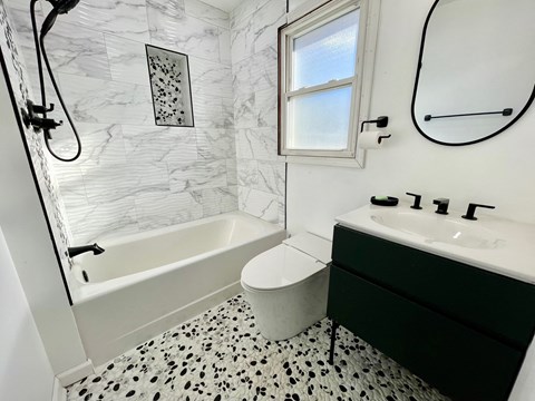 a bathroom with black and white tile and a tub and sink