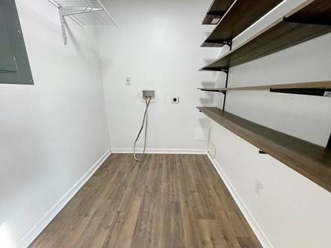 a room with white walls and wood flooring and a white wall with a shelf