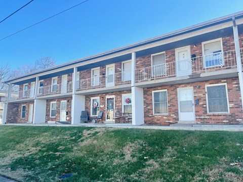 the front of a brick apartment building with a lawn