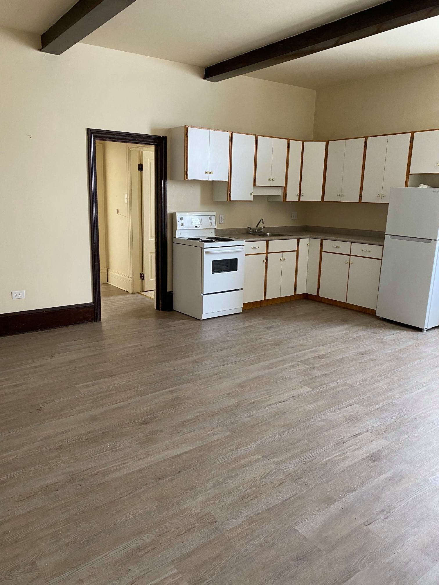 an empty kitchen with white appliances and white cabinets