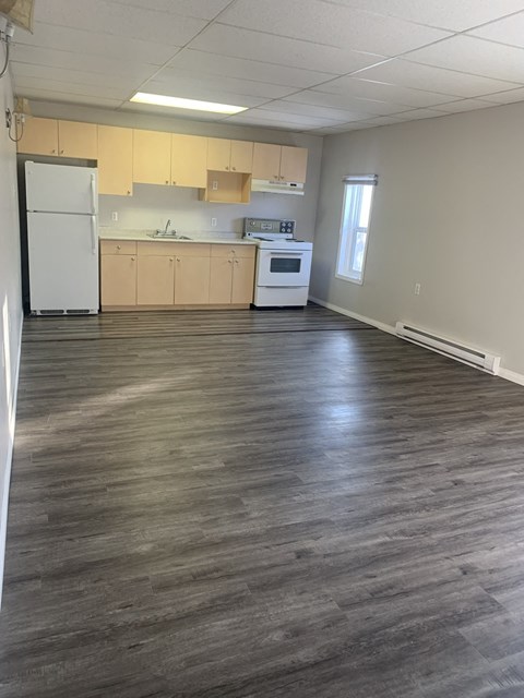 an empty kitchen and living room with wood floors