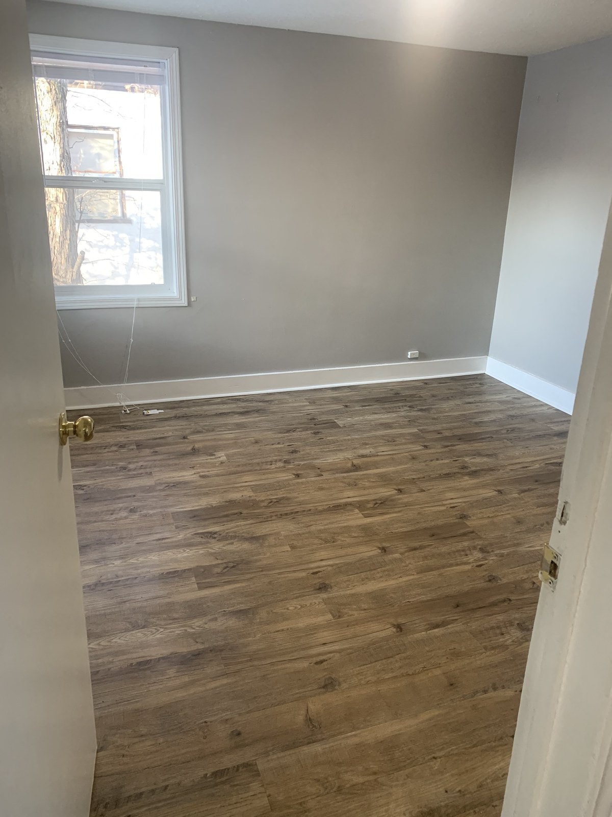 an empty room with wooden floors and a window
