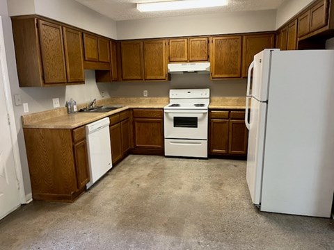 A kitchen with brown cabinets and white appliances.