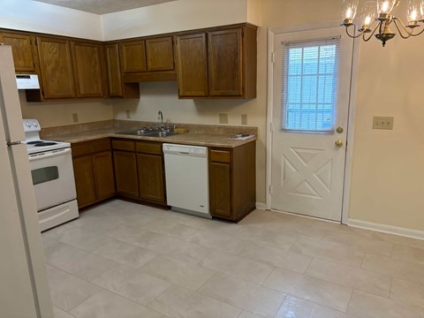 A kitchen with wooden cabinets and a white door.