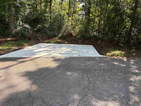 A cracked asphalt surface with trees in the background.