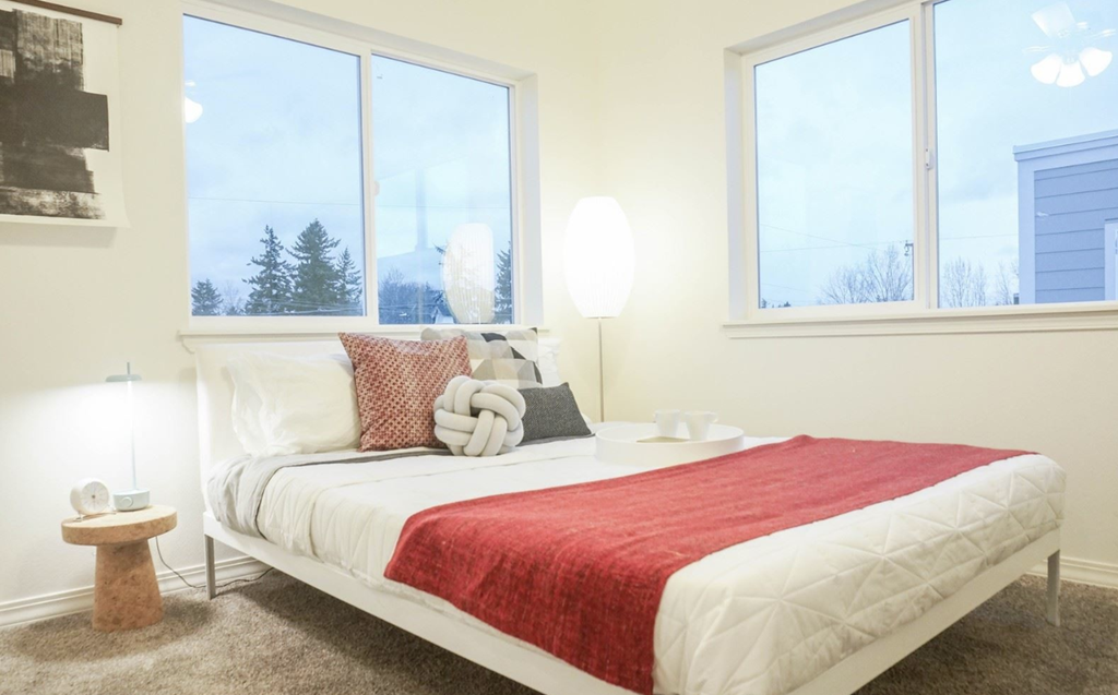 a bedroom with a bed and three large windows