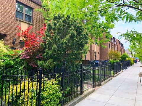 a sidewalk in front of a wrought iron fence