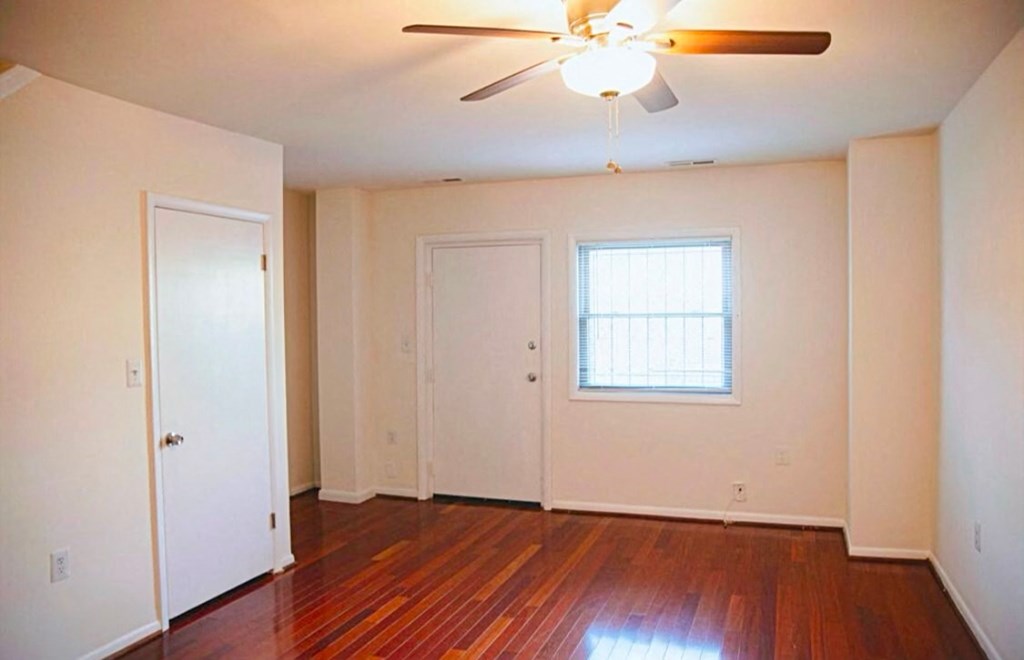 the living room of an empty house with wooden floors and a ceiling fan