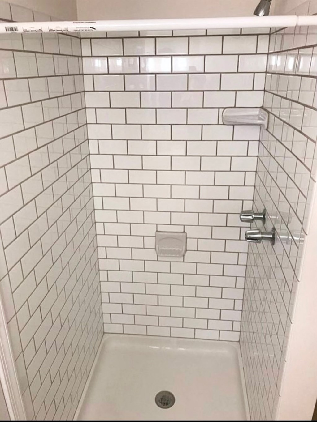a white tiled shower with white subway tiles and a shower curtain