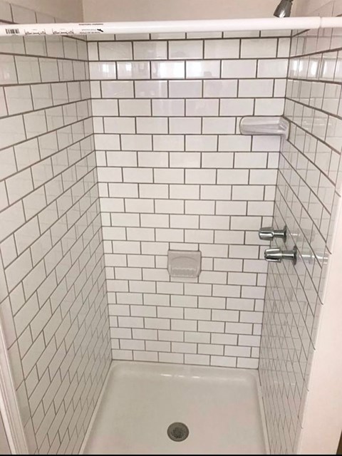 a white tiled shower with white subway tiles and a shower curtain