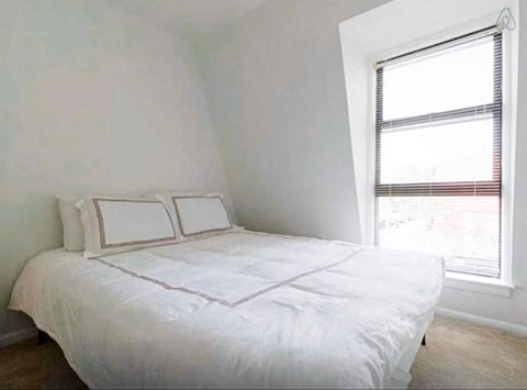 a small bedroom with a bed and a window