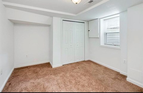 an empty bedroom with a closet and a window