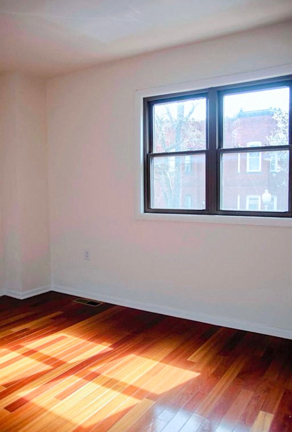 an empty room with a window and wooden floors