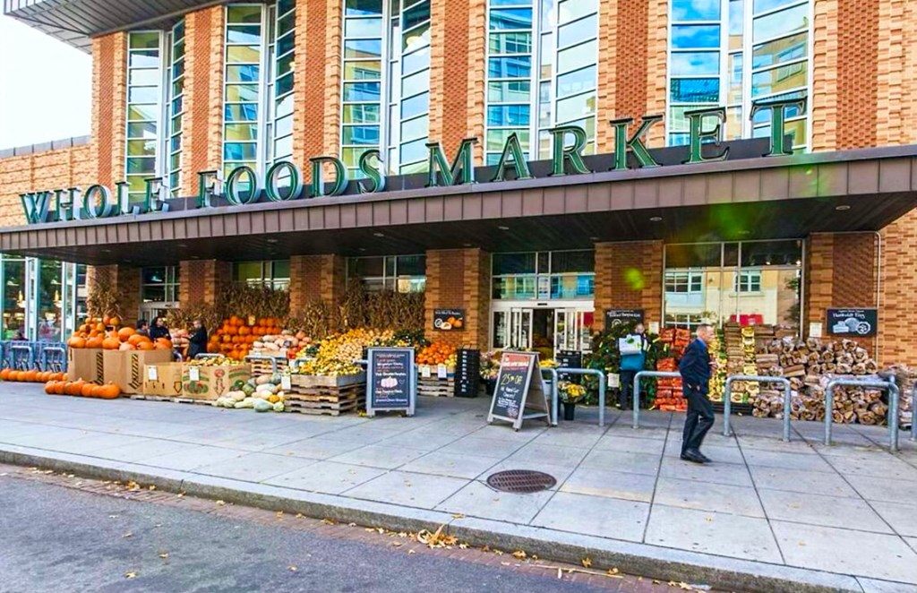 a man standing outside of a market with fruits and vegetables