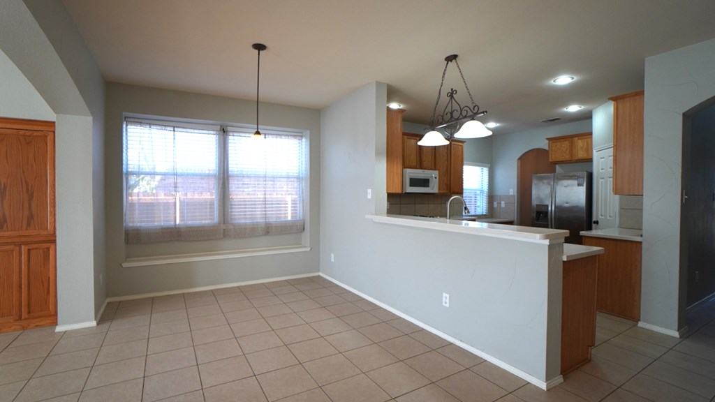 A kitchen with a white counter and wooden cabinets.