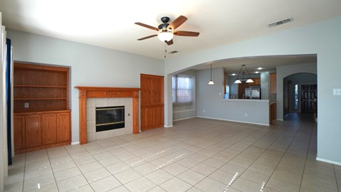 A spacious living room with a fireplace and a ceiling fan.