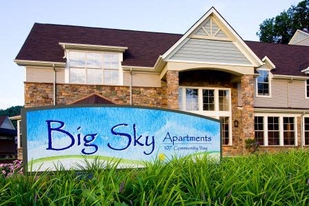 a big sky apartments sign in front of a house