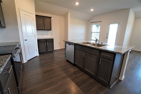 A kitchen with dark wood floors and a granite countertop.