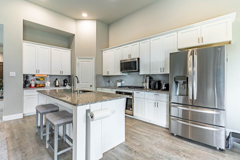 a large kitchen with stainless steel appliances and white cabinets