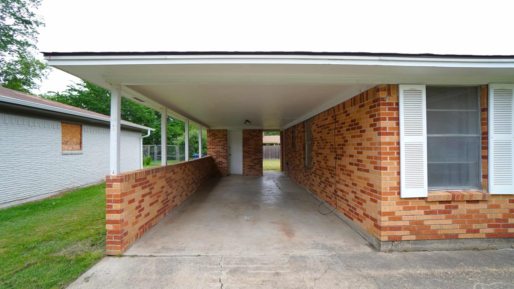 the front porch of a brick house with a concrete walkway