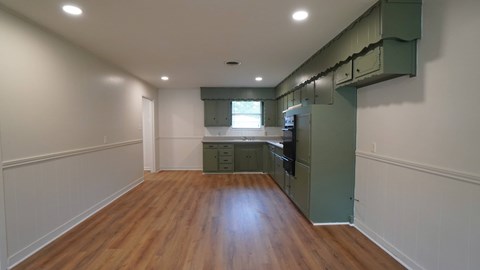 a kitchen with green cabinets and a wooden floor