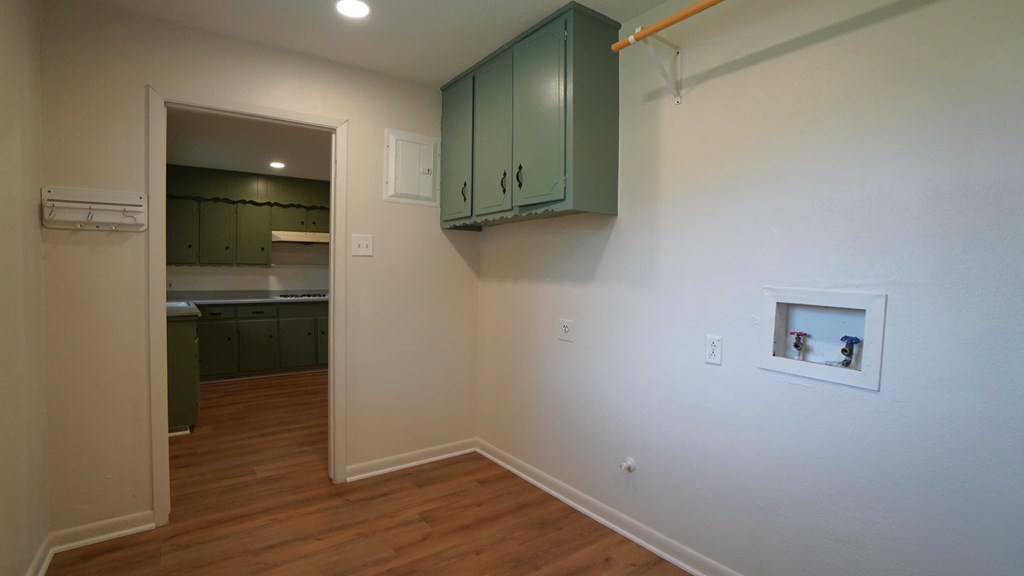 a kitchen and living room with white walls and wood floors