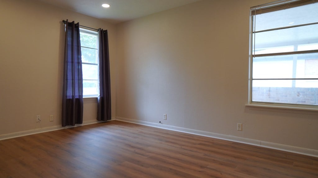 an empty living room with wood floors and a window