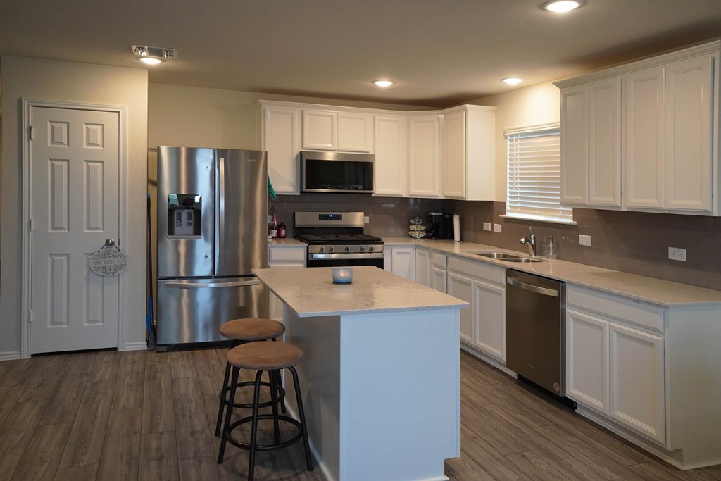 A kitchen with white cabinets and a wooden island.