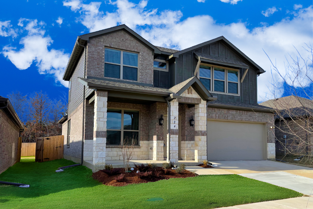 A modern house with a grey and brown exterior and a green lawn.
