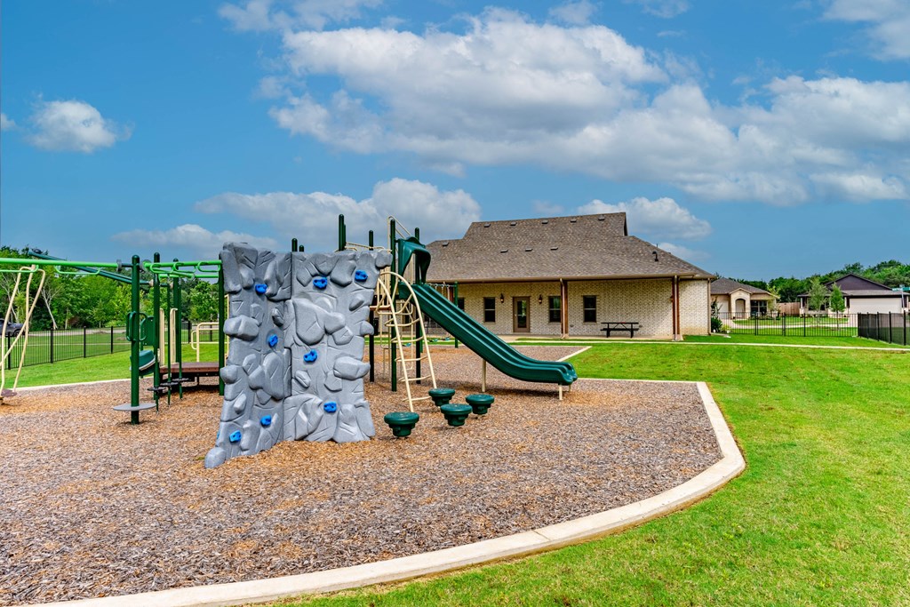 a playground with a play set and a house in the background