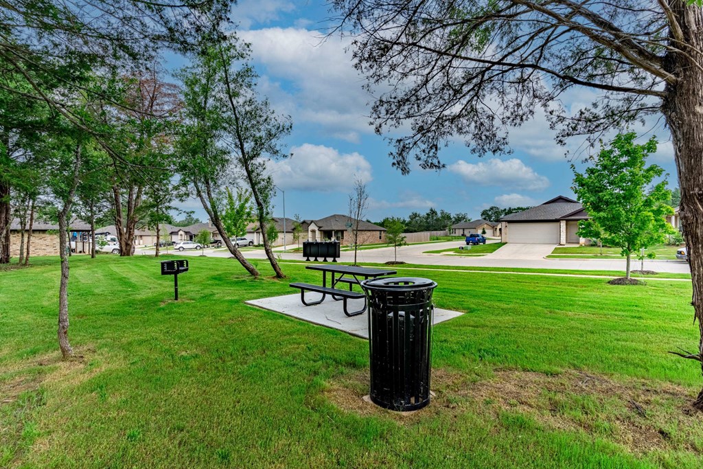 a park with a picnic table and a trash can