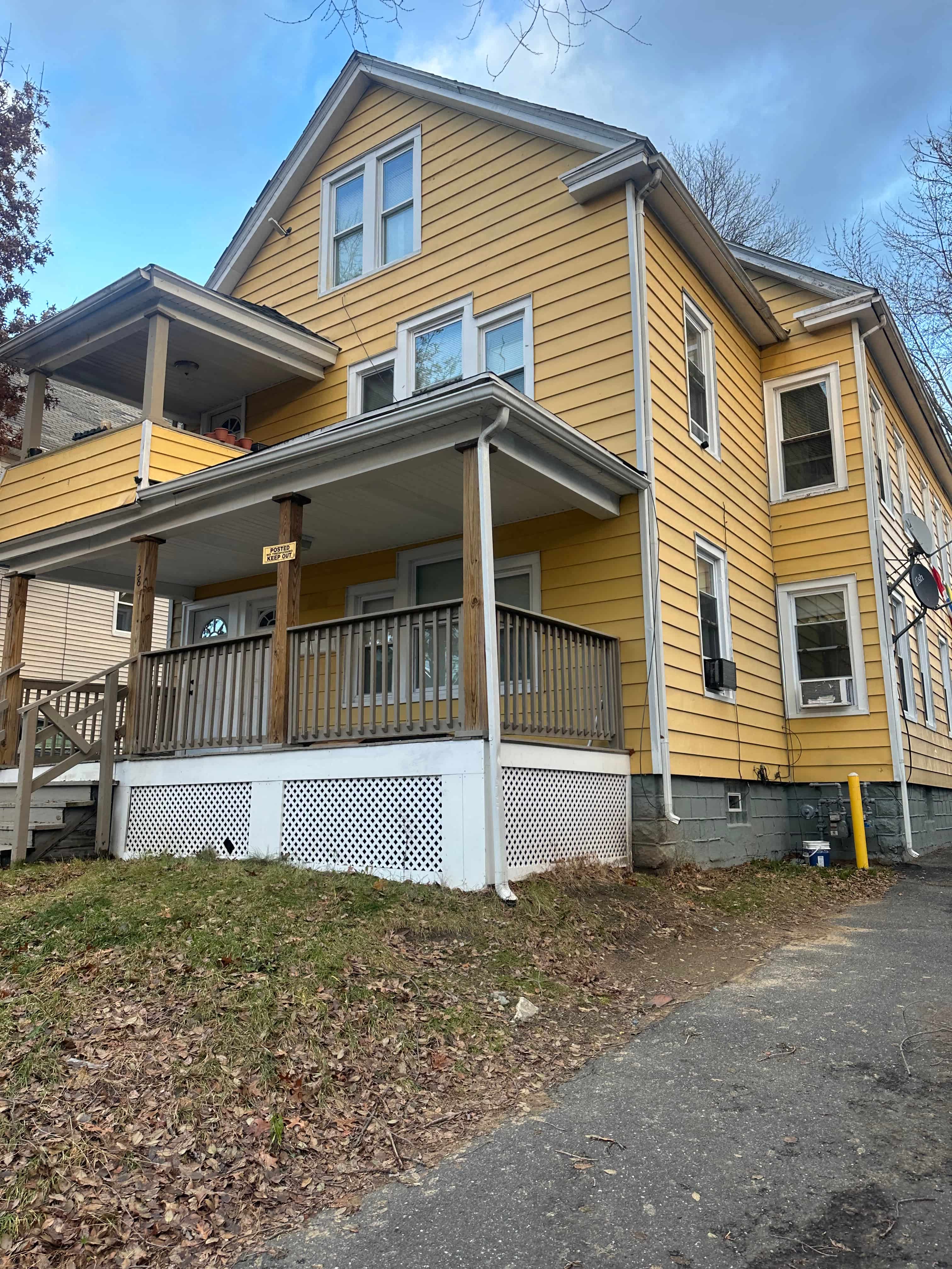 a yellow house with a porch and a sidewalk
