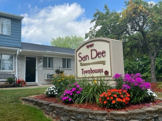A sign for San Dee Townhouses is surrounded by flowers.