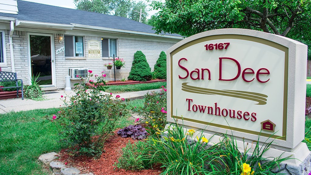 A sign for San Dee Townhouses stands in front of a house.