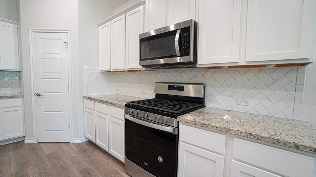 A kitchen with a black stove and a microwave above it.