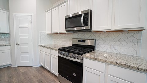 A kitchen with a black stove and a microwave above it.