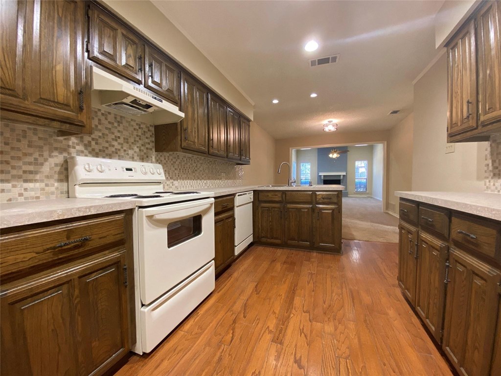 A kitchen with wooden cabinets and a white stove top oven.