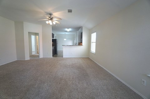 A spacious room with a ceiling fan and carpeted floor.