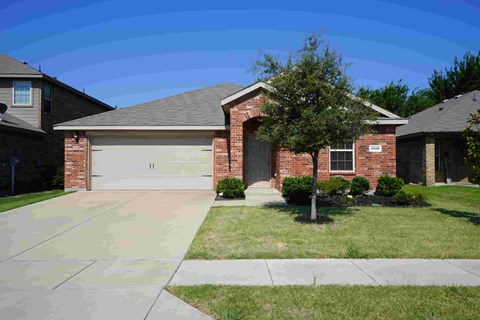 a brick house with a garage door and a lawn