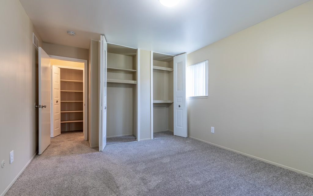 an empty room with a closet and a window