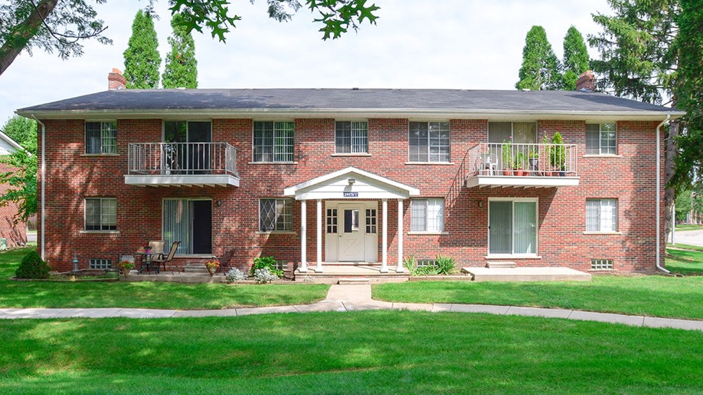a red brick house with a lawn in front of it