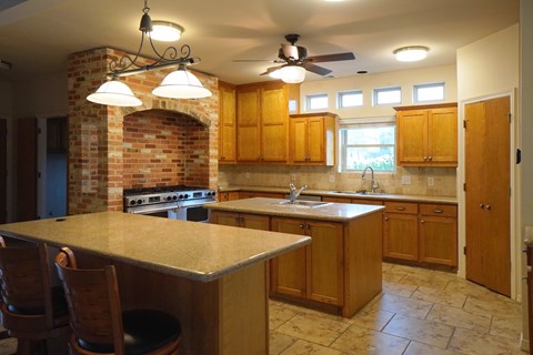 A kitchen with a brick chimney and wooden cabinets.