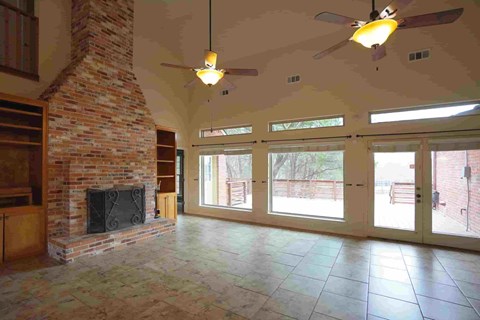 A living room with a fireplace and a ceiling fan.
