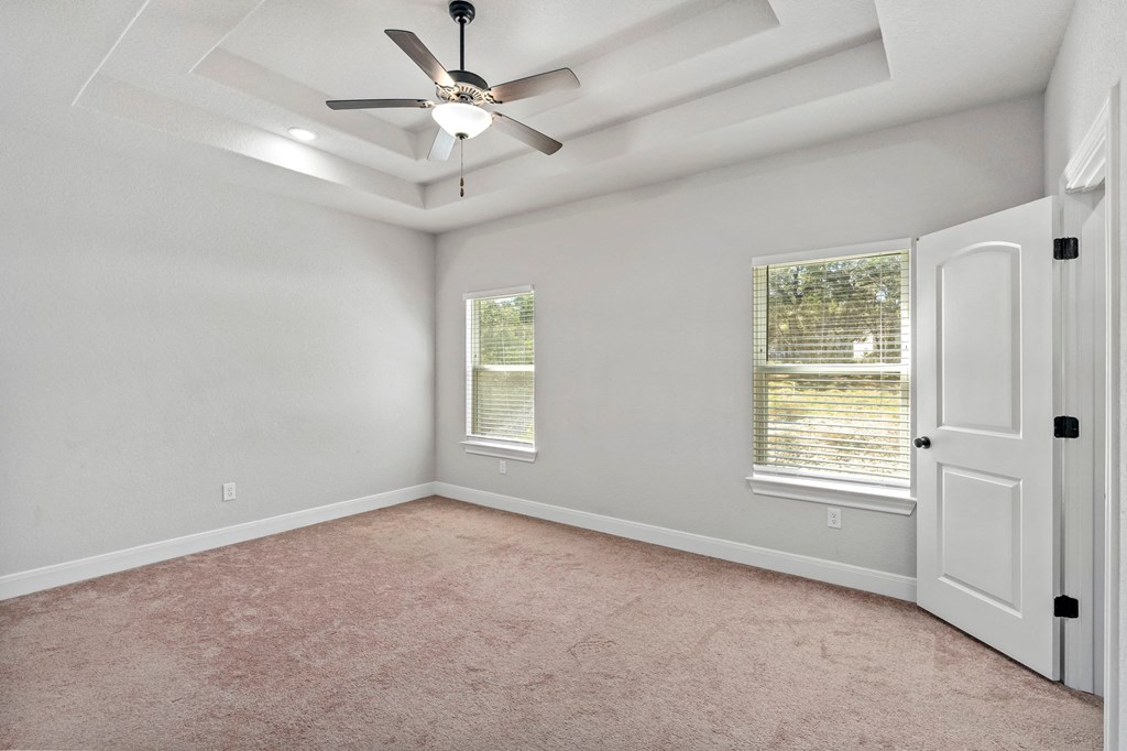 an empty bedroom with a ceiling fan and window